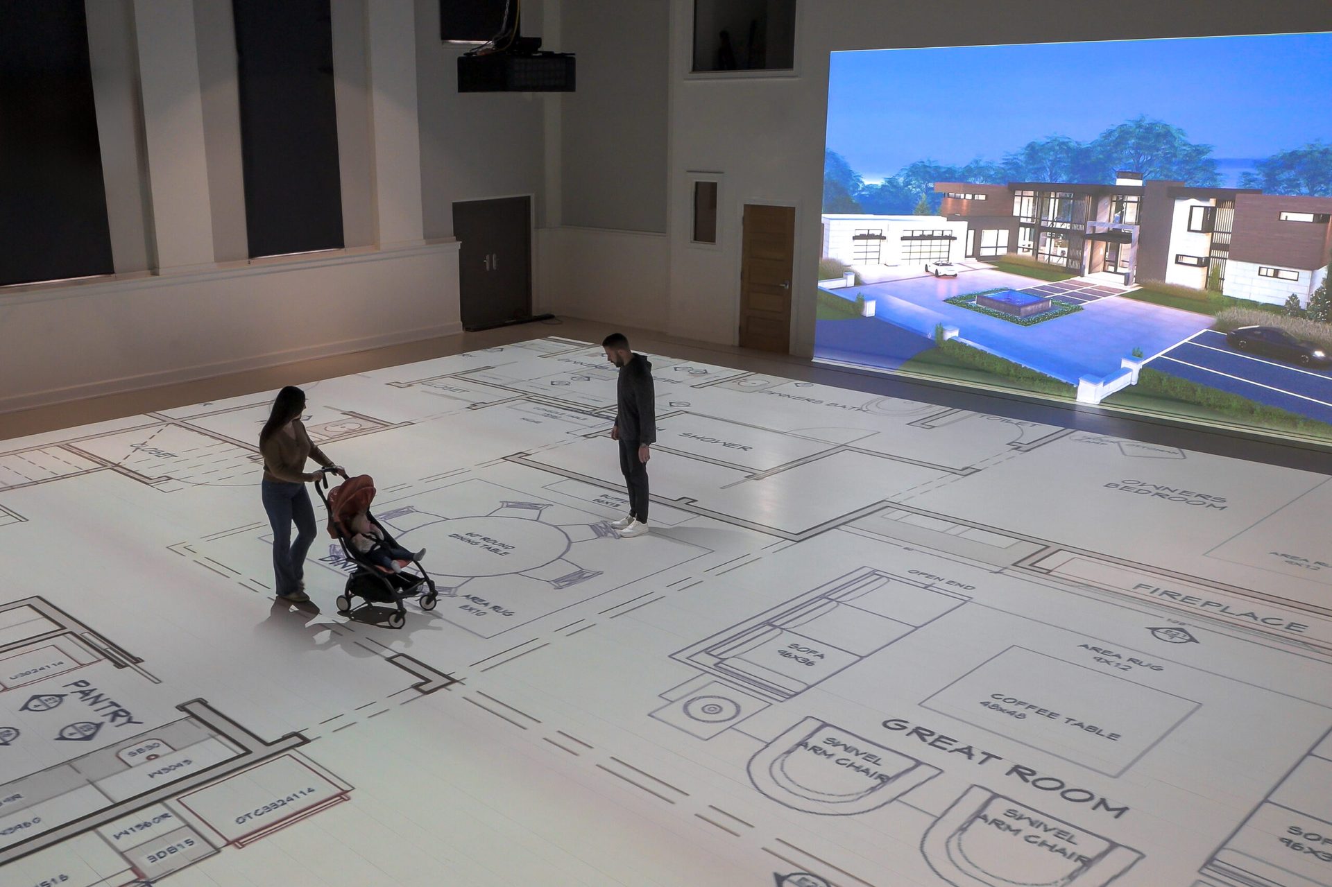 A family walking their home's floor plan projected at full scale on the studio floor