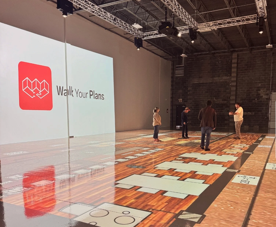 People walking through a restaurant floor plan at full scale inside a Walk Your Plans studio